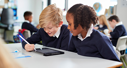 Two primary pupils working together on a tablet in a classroom